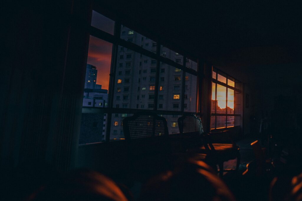 A warm sunset viewed through a window, with sunlight casting soft orange light into a room.