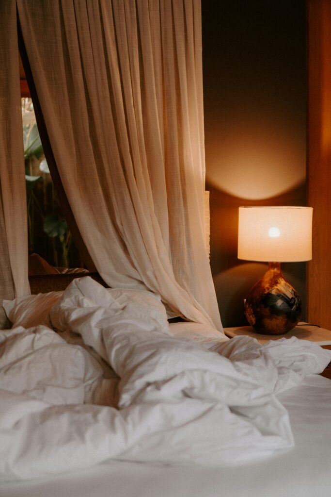 A cozy bedroom with warm lighting, soft bedding, and neutral tones creating a calm and comfortable atmosphere.